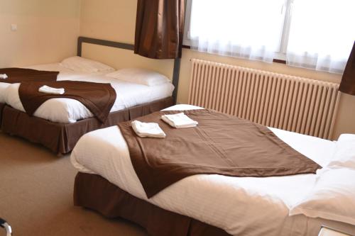two beds in a hotel room with towels on them at Hôtel Continental in Vierzon
