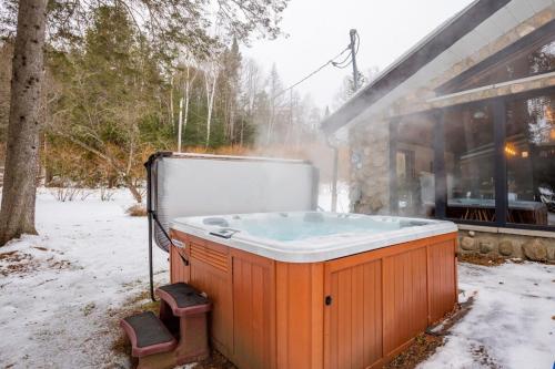 a hot tub sitting outside of a house in the snow at Le Cozy de St-Come - Lake front- boats in Saint Come