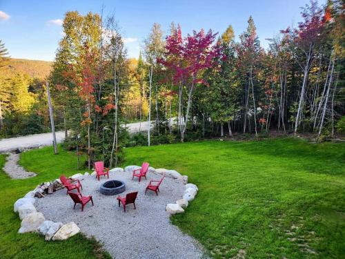 a fire pit with red chairs in a yard at Chalet Isatis - SPA - Access to the Lake in Saint Come