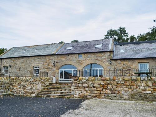 an old stone house with a stone wall at The Byres in Greenhaugh