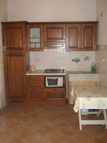 a kitchen with wooden cabinets and a stove and a table at Poggio Picchio in Bibbona