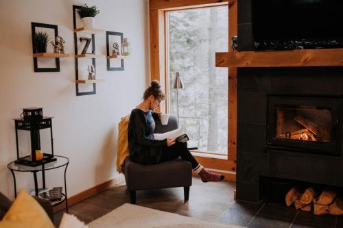 a woman sitting in a chair in a living room with a fireplace at Zazz - For precious moments with family or friends in Chertsey