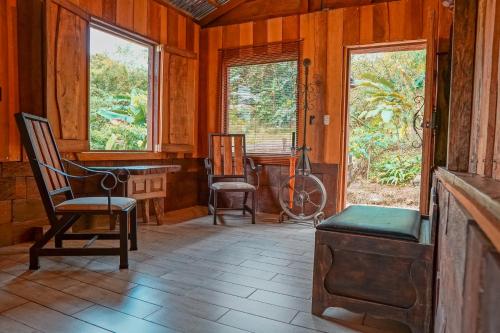 a room with two chairs and windows in a cabin at La Tigra Rainforest Lodge in Fortuna