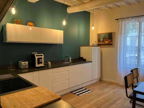 a kitchen with white cabinets and a green wall at maison pierre centre Uzès climatisation garage in Uzès
