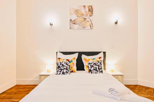 une chambre avec un grand lit blanc avec des oreillers dans l'établissement Grand appartement Parc des princes Paris 16, à Paris