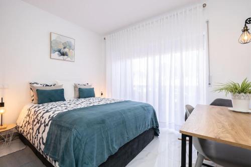 a white bedroom with a bed and a table at Parque dos Reis, apartment 3 B in Monte Gordo