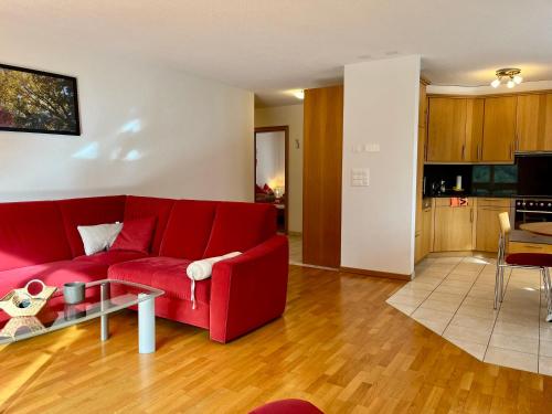 a living room with a red couch and a table at Apartments Residenz Iris in Leukerbad