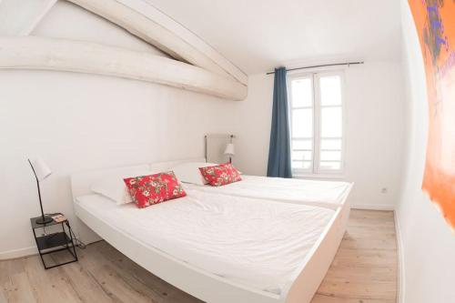 - un lit blanc avec des oreillers rouges dans une chambre blanche dans l'établissement Appartement Avignon du Château de Marrets, à Avignon