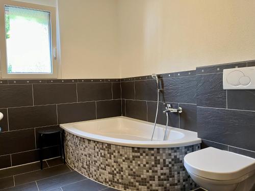 a bathroom with a bath tub and a toilet at Apartments Residenz Iris in Leukerbad