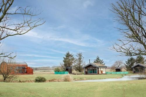 a group of houses in a field with trees at Wildflower Eco Lodges in Fraserburgh