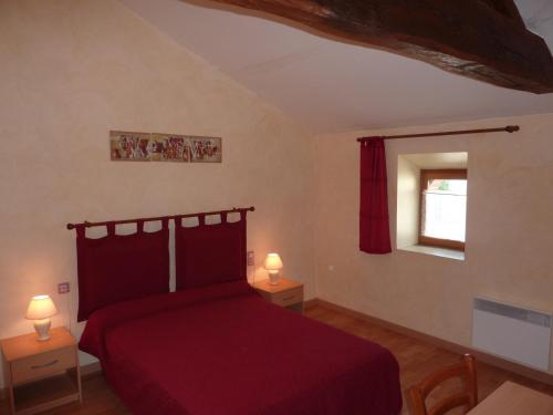 ein Schlafzimmer mit einem roten Bett mit zwei Tischen und einem Fenster in der Unterkunft Gîte de l'Ivronnière in La Ronde