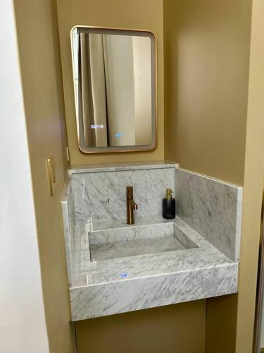 La salle de bains est pourvue d'un lavabo en marbre et d'un miroir. dans l'établissement Otentik Art Déco, à Metz