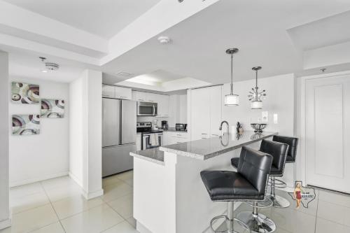 a white kitchen with black chairs at a counter at Bahia Mar-Solare Tower, Beachfront Resort with Two Pools in South Padre Island