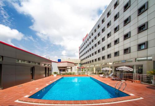 un hotel con piscina di fronte a un edificio di Ibis Lagos Ikeja a Ikeja