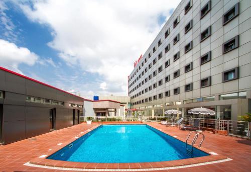 a hotel with a swimming pool in front of a building at Ibis Lagos Ikeja in Ikeja