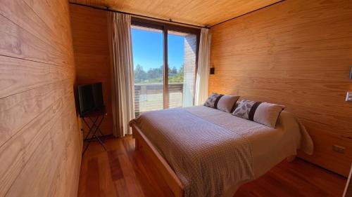 ein Schlafzimmer mit einem Bett und einem großen Fenster in der Unterkunft Casa Morro Punta de Lobos in Pichilemu