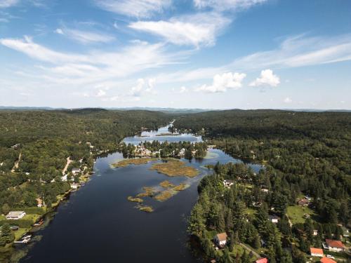 an aerial view of a lake with trees and houses at Le Lac Apaisant - Rustic Haven by the Water in Saint-Calixte