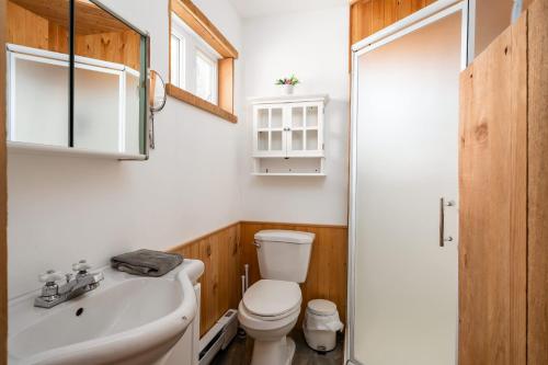 a bathroom with a white toilet and a sink at Le Lac Apaisant - Rustic Haven by the Water in Saint-Calixte