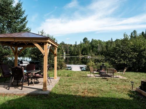 a gazebo with a table and chairs in a yard at Le Lac Apaisant - Rustic Haven by the Water in Saint-Calixte