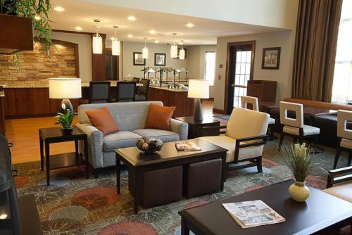 a living room with a couch and tables and chairs at Staybridge Suites Auburn Hills by IHG in Auburn Hills