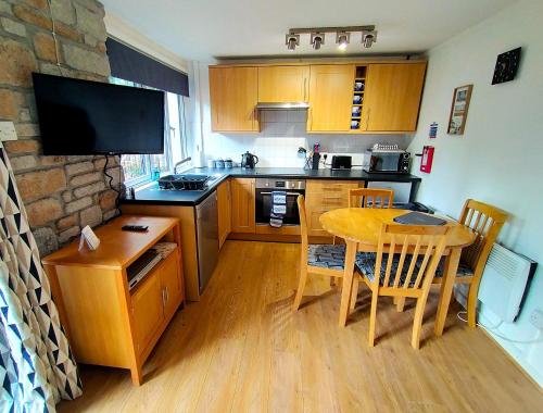 a kitchen with wooden cabinets and a table with chairs at Woodland View - Families & Pets in Uny Lelant