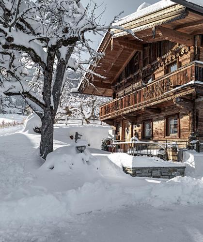 a log cabin covered in snow next to a tree at Alpen-Chalet-Pankraz in Fügenberg