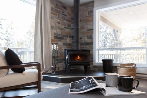 a living room with a fireplace and a table with a newspaper at Entre Monts et Lac - lac - Lake front & Volleyball in Saint Adolphe D'Howard