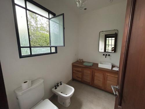 ein Badezimmer mit Toilette, Waschbecken und Spiegel in der Unterkunft Praderas de San Lorenzo in El Durazno