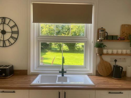 a kitchen with a sink and a window with a clock at Trosnant, Ewyas Harold in Hereford