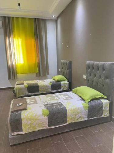 two beds in a room with yellow and green curtains at Villa Privée 1 Marrakech Piscine Chauffée En Option Sans Vis-à-vis pour famille et couple marié uniquement in Marrakech