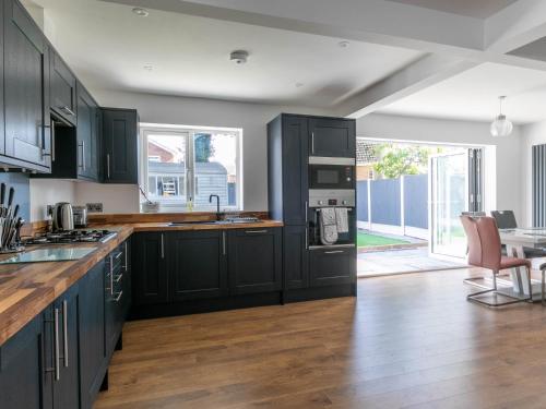 a kitchen with black cabinets and a table and chairs at Seaside Family Bungalow for 5 people with garden and driveway parking in Kent