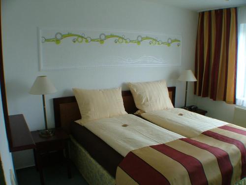 a hotel room with two beds and two lamps at Hotel garni Pension Zur Lutherstadt in Lutherstadt Eisleben