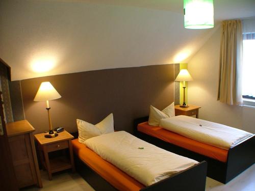 a hotel room with two beds and two lamps at Hotel garni Pension Zur Lutherstadt in Lutherstadt Eisleben