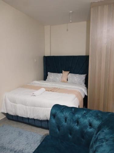 Un dormitorio con una cama grande y un sofá azul. en Zen Place, en Nairobi