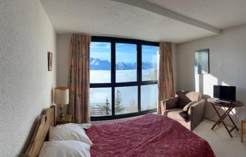 a bedroom with a bed and a large window at Appartement avec vue exceptionnelle au pied des pistes in L'Alpe-d'Huez