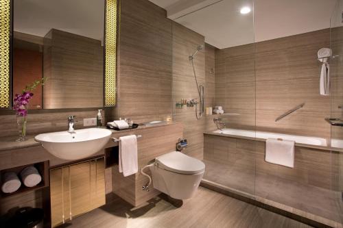 a bathroom with a sink and a toilet and a tub at Ascott Waterplace Surabaya in Surabaya