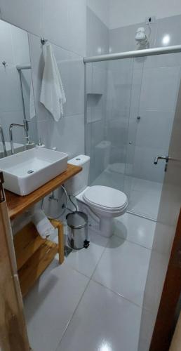 a white bathroom with a sink and a toilet at Pousada Athena in Palmeiras