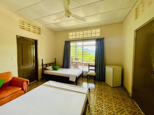 a room with two beds and a couch and a window at Casa campestre La Victoria-Private Village in Tocaima