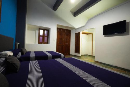 a bedroom with two beds and a flat screen tv at Hotel Posada Don Matías in Oaxaca City