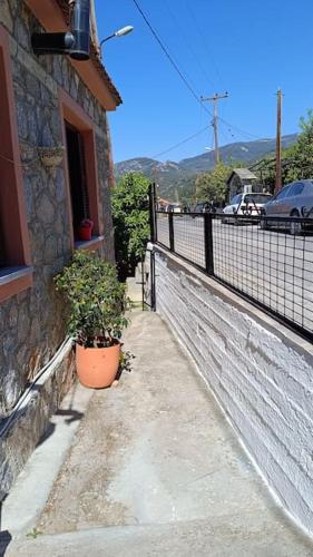 a building with a potted plant next to a fence at Traditional house at Pelion seaside in Agria