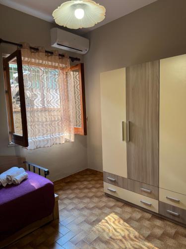 a bedroom with a bed and a cabinet and a window at Casa Archi in Cefalù