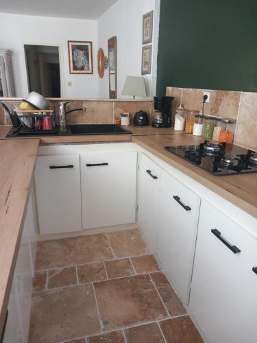 une cuisine avec des armoires blanches et un sol carrelé dans l'établissement Appartement au coeur du centre historique, à Narbonne