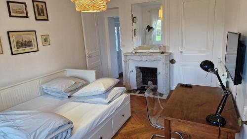 Croix-MareにあるGite dans une maison normandeのベッドルーム(ベッド1台、デスク、暖炉付)