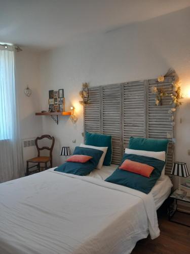 une chambre avec un grand lit blanc avec des oreillers bleus dans l'établissement Appartement au coeur du centre historique, à Narbonne