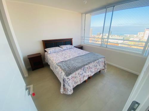 a bedroom with a bed and a large window at Amtaya Inmobiliaria in Iquique