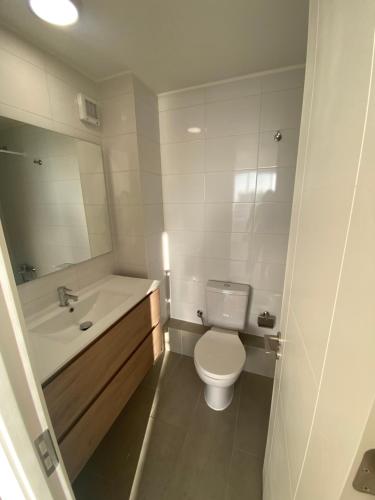 a white bathroom with a toilet and a sink at Amtaya Inmobiliaria in Iquique