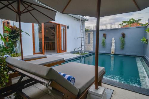 a swimming pool with a bed and an umbrella at Villa Dua Warna Dencarik in Lovina