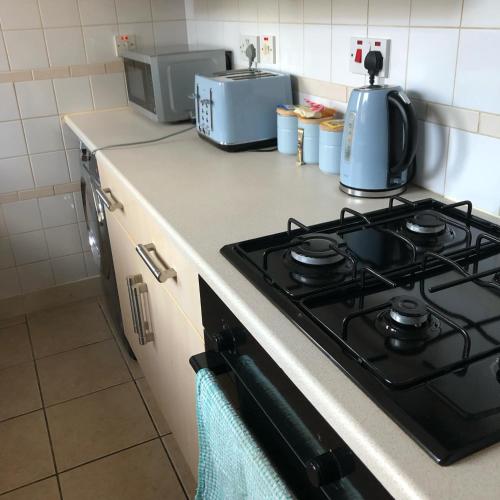 a kitchen counter with a stove and a microwave at Spacious 2-Level Home by the Beach & Transport in Methil