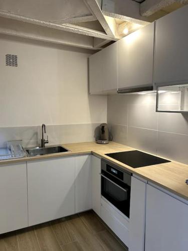 une cuisine avec des armoires blanches et un évier dans l'établissement Le Charmant - Appartement Calme et Cosy au coeur de Toulouse - Proche Transports, à Toulouse