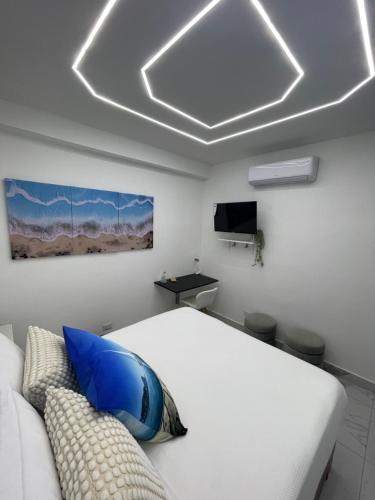 ein Schlafzimmer mit einem weißen Bett und einem Fernseher in der Unterkunft Tiny Home-El Pueblito in San Felipe de Puerto Plata
